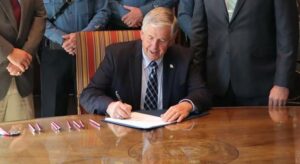 Governor Mike Parson signing a law document.