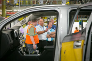 People talking at a car manufacturing warehouse.