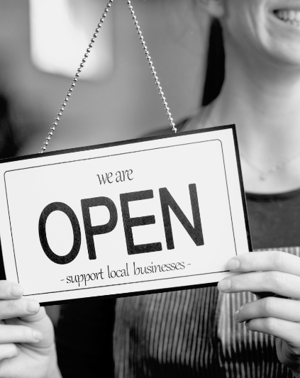 Woman holding a 'We are open, Support Local Businesses' sign.