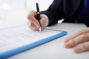 Business person signs contract with black pen