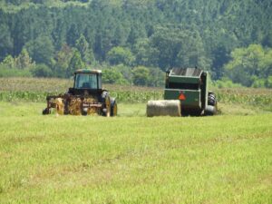 Farm equipment working in field baling hay