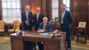 Gov. Mike Parson signs SB 20. He is accompanied by Louis Landwehr, Winter-Dent & Company, Doyle Edwards, Brewer Science, and Trevor Monnig, president of the Heart of America Chapter of The ESOP Association.