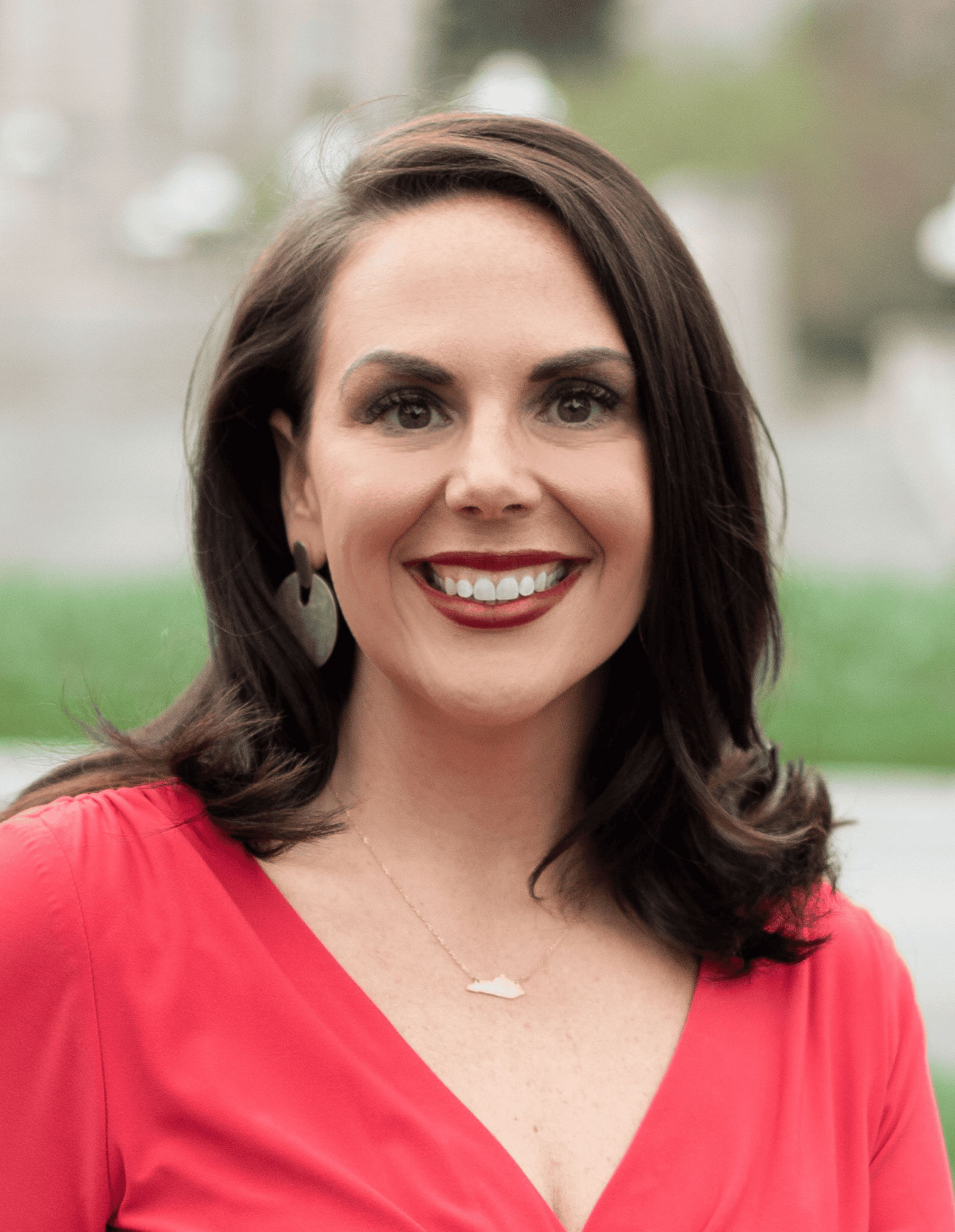 Brunette woman smiling with red blouse.